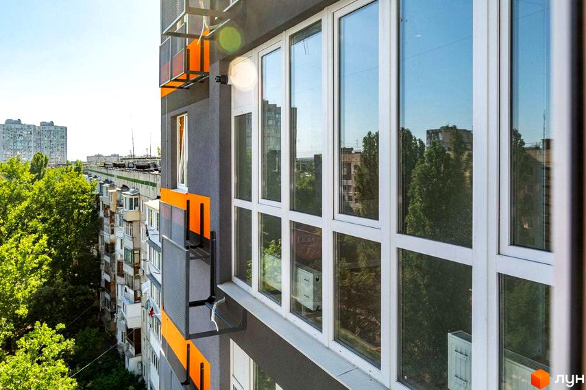 Зовнішній вигляд будинку в Житловому комплексі Схід з великими вікнами. Вигляд з вікна на сусідні будинки та зелені насадження.