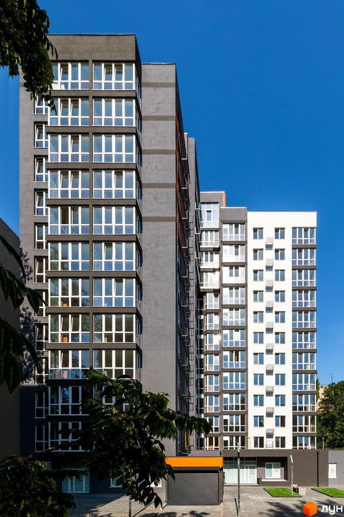 Зовнішній вигляд багатоповерхового будинку в Житловому комплексі Схід. Фасад будинку сірого та білого кольорів, великі вікна.
