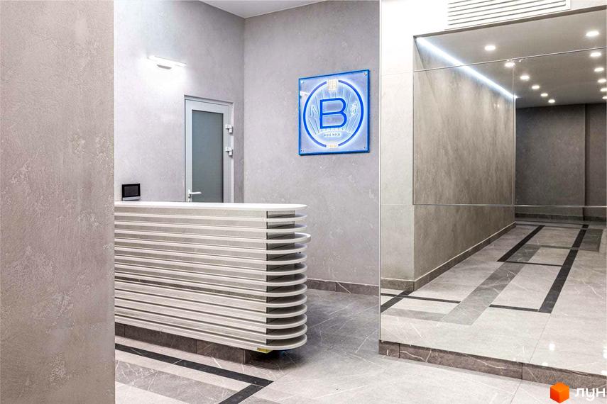 Фото ресепшену в Житловому комплексі Схід. Інтер'єр з ресепшеном та логотипом комплексу на стіні.