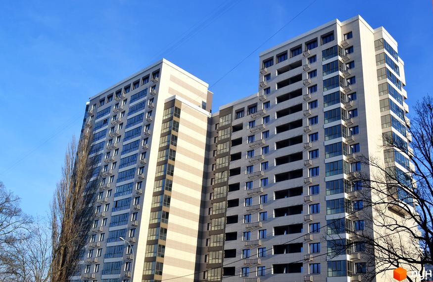 Житловий комплекс Островського, 40 з сучасними фасадами та великими вікнами. Прибудинкова територія озеленена деревами.