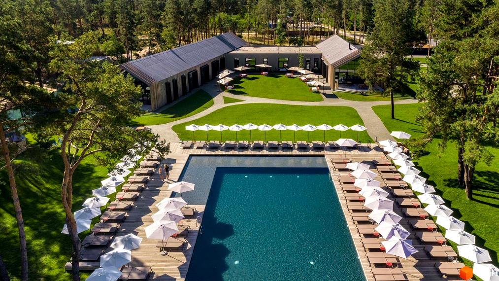 КМ SHELEST.home: вид зверху на басейн з шезлонгами та парасольками, а також на будівлі комплексу та зелену галявину.