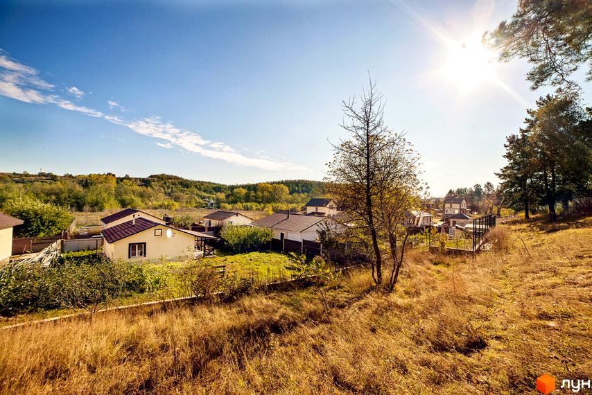 Котеджне містечко Лисичкина діброва. Мальовничий вид на одноповерхові будинки з коричневими дахами та зелену прибудинкову територію з деревами.