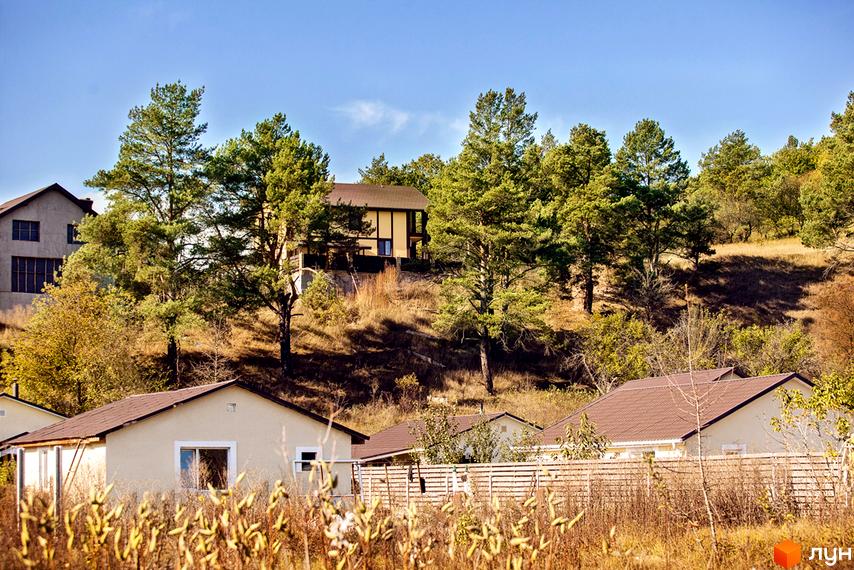 Котеджне містечко Лисичкина діброва. Зовнішній вигляд будинків та прибудинкова територія з деревами та парканом.