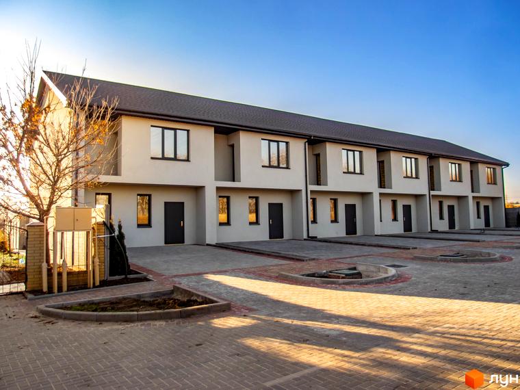 Таунхаус „Європейський“: ряд двоповерхових таунхаусів зі світлими фасадами та темними дахами. Прибудинкова територія вимощена бруківкою, є зелені насадження.