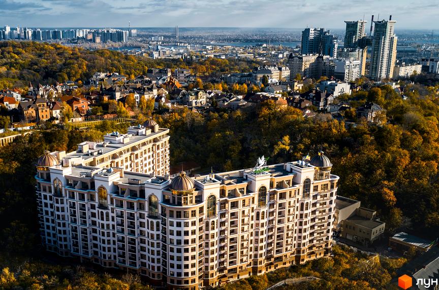 Житловий комплекс Pechersk Plaza з великою кількістю вікон та куполами на даху. Навколо будівлі розташована зелена зона з деревами.