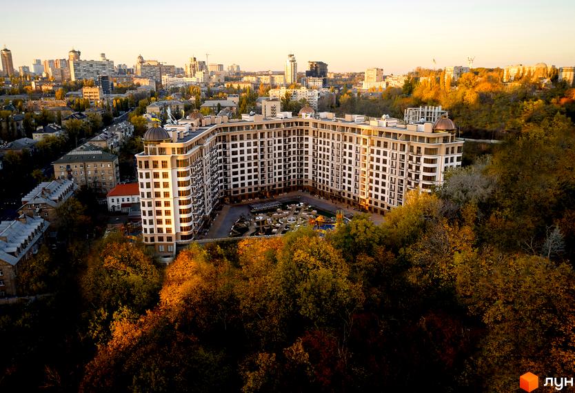 Житловий комплекс 52 Перлина (Pechersk Plaza) з видом на місто. Будинок має багато поверхів з великою кількістю вікон. На прибудинковій території є дитячий майданчик.