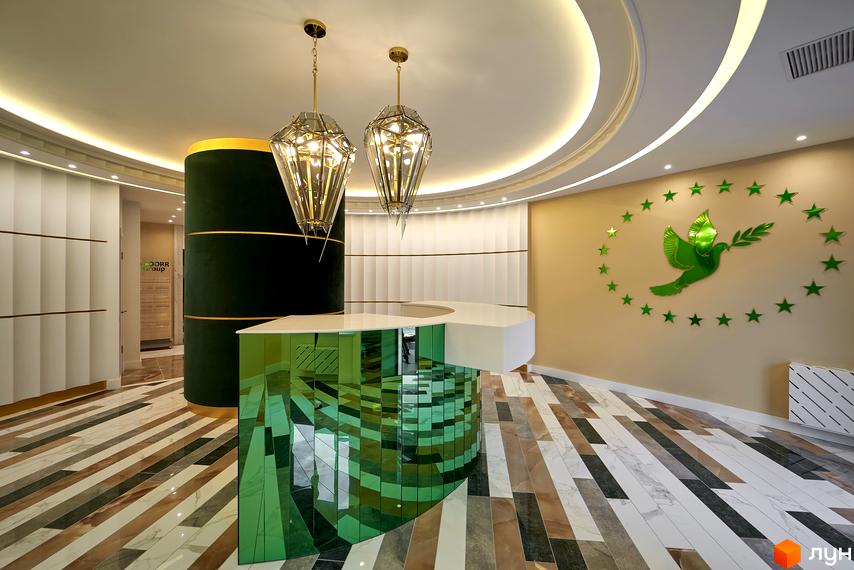 Інтер'єр холу в ЖК 52 Перлина. Стіни оздоблені декоративними панелями, підлога з мармурової плитки. Стійка ресепшен з дзеркальною поверхнею.