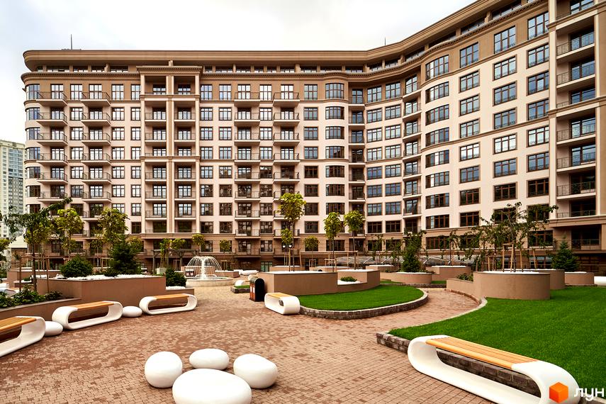 Житловий комплекс 52 Перлина (Pechersk Plaza) з фасадом у світлих тонах та балконами. На прибудинковій території розташовані зони відпочинку з лавками та газонами.