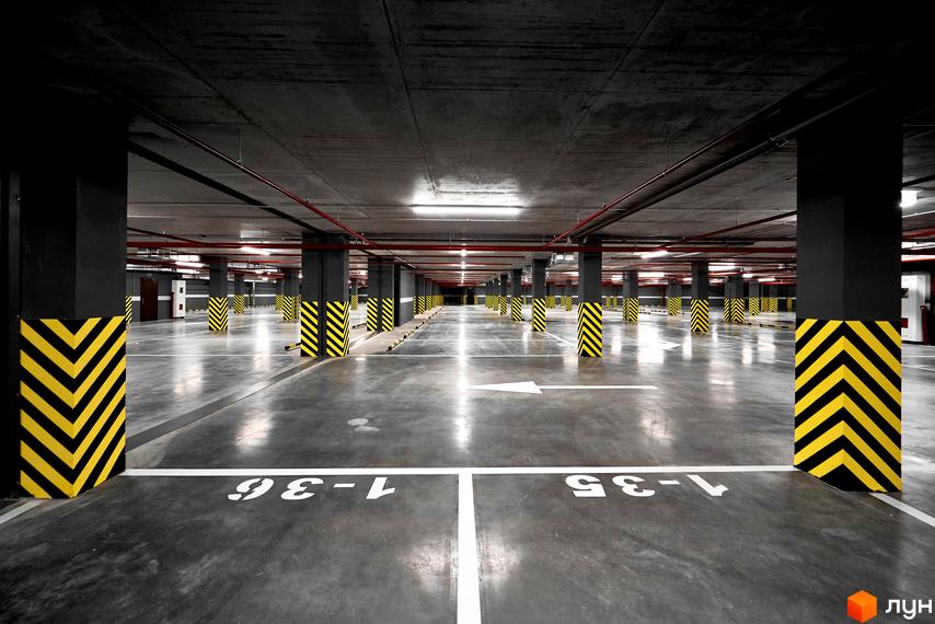 Підземний паркінг в ЖК 52 Перлина (Pechersk Plaza). Просторий паркінг з розміткою та колонами з жовто-чорною розміткою.