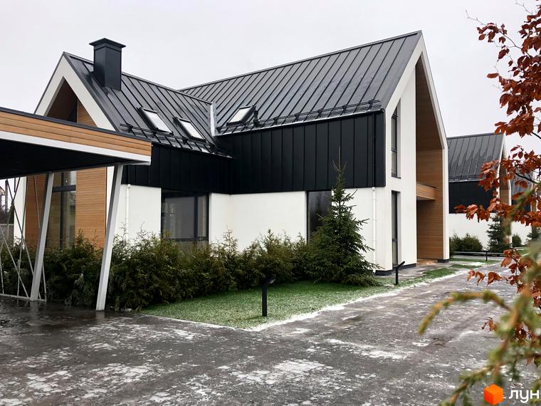 Котеджне містечко КМ Hill Park. Сучасний будинок з чорним металевим дахом та білими стінами, оточений зеленню та доглянутою територією.