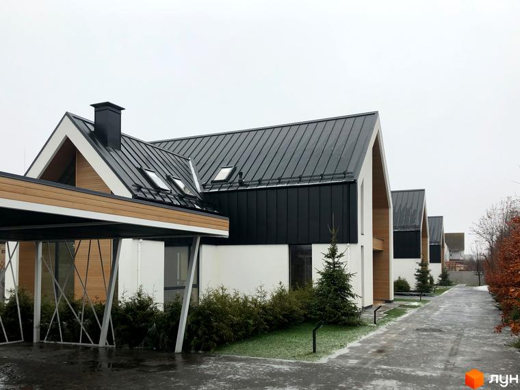 Котеджне містечко КМ Hill Park: фасади будинків з чорним металевим дахом та дерев'яними елементами, доглянута прибудинкова територія з ялинками та доріжками.