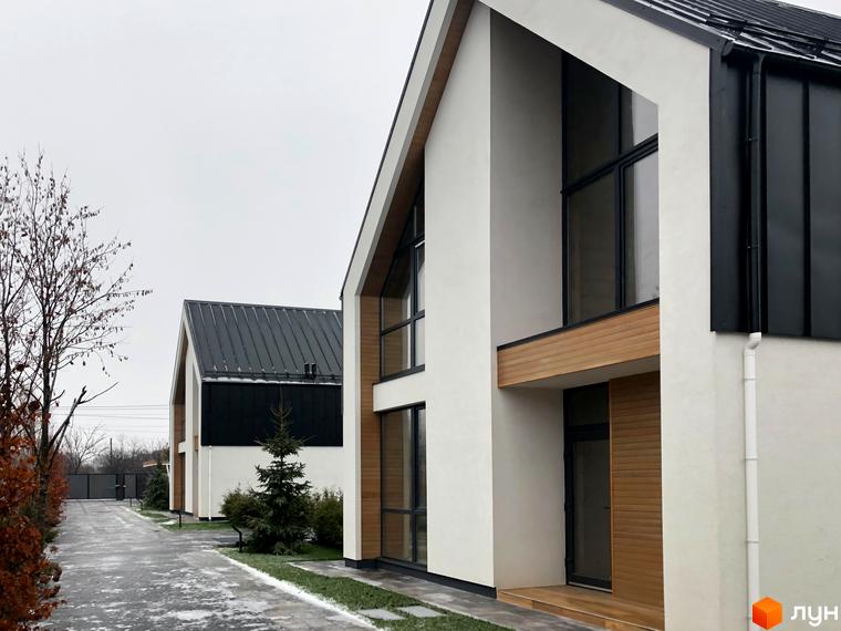 Котеджне містечко КМ Hill Park: фасади будинків з панорамними вікнами та дерев'яними елементами, доглянута прибудинкова територія з ялинками та доріжками.