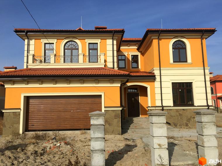 Котеджне містечко КМ Італійський квартал. Фасад будинку в оранжевих тонах з коричневим гаражем та червоною черепицею.