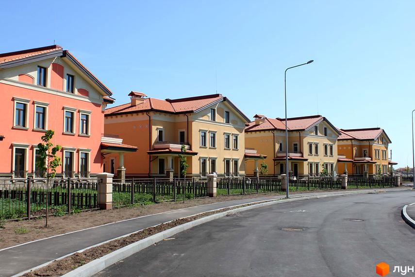 Котеджне містечко Італійський квартал: будинки з жовтим та помаранчевим фасадом під червоним дахом. Поруч дорога та доглянута територія.