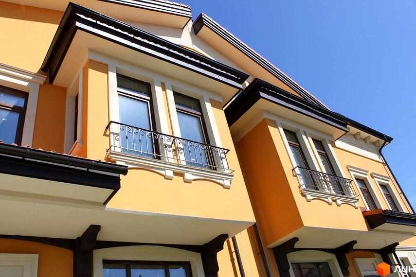 Фасад будинку КМ Італійський квартал з балконами та вікнами. Зовнішній вигляд новобудови під блакитним небом.