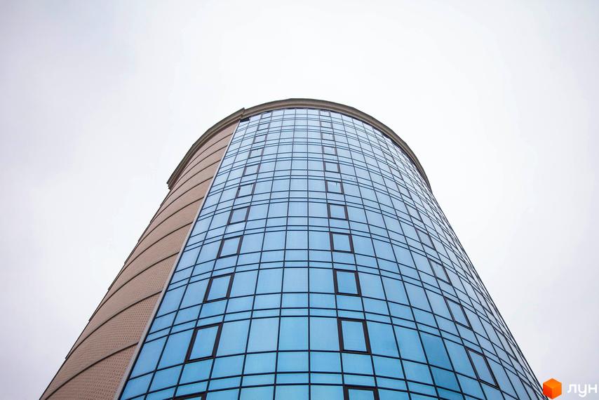 Зображення фасаду Житлового комплексу Paradise з великими вікнами. Вид знизу на будівлю та сіре небо.