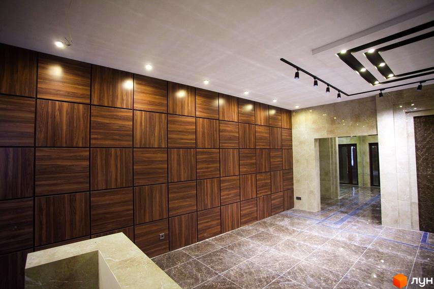 Інтер'єр кімнати в Житловому комплексі Paradise з дерев'яними панелями на стінах та плиткою на підлозі. Вигляд кімнати з освітленням та дверима вдалині.