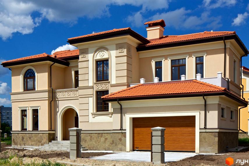 Котеджне містечко КМ Італійський квартал. Фасад двоповерхового будинку з червоною черепицею та кам'яним цоколем. Навколо будинку облаштована прибудинкова територія.