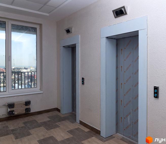 Новобудова Ярославів Град. Коридор з двома ліфтами та вікном з видом на місто.