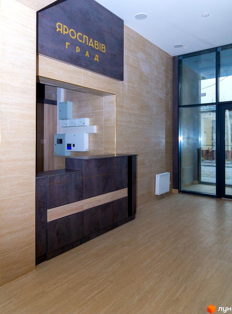 Житловий комплекс Ярославів Град. Сучасна рецепція з золотими літерами на темній вивісці та облицюванням стін під мармур.