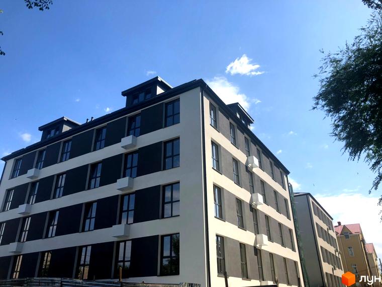 Фото фасаду Клубних будинків „На Генерала Пушкіна“. Багатоповерхова будівля з великими вікнами та світлим оздобленням.