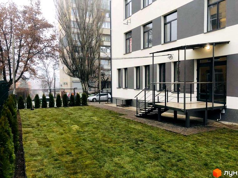 Зовнішній вигляд Клубні будинки „На Генерала Пушкіна“ та прибудинкова територія з газоном і декоративними насадженнями.