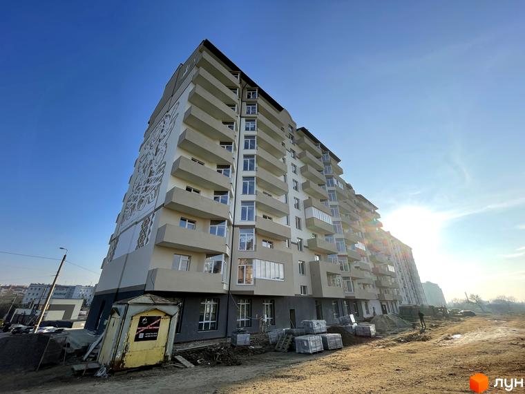 Багатоповерховий житловий комплекс на вул. Горбачевського з балконами та декоративним фасадом. Будівництво на сонячному майданчику з будівельними матеріалами.