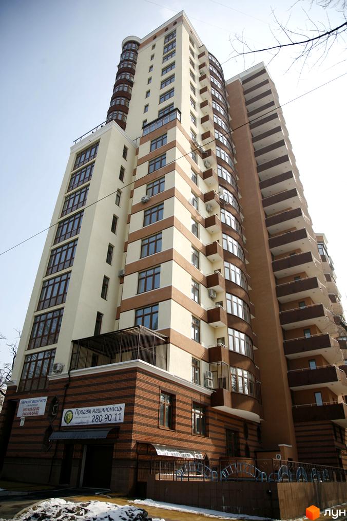 Житловий комплекс на вул. Коперника, 11, з фасадом з великими вікнами та балконами. Прибудинкова територія з паркувальними місцями та огорожею.