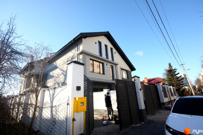 Дуплекс „Чорна Перлина“ – двоповерховий будинок сірого та білого кольору з темним дахом та великими вікнами. Територія огороджена парканом, біля будинку є зелена зона та автомобіль.