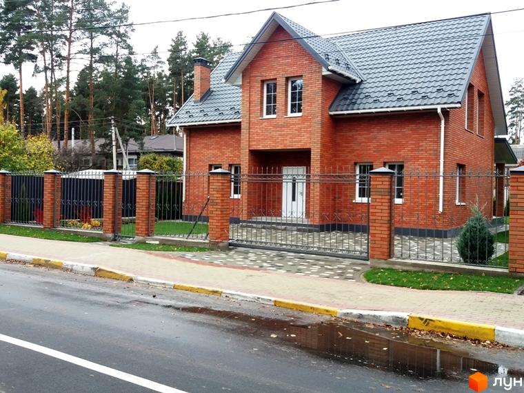 Котеджне містечко КМ Pine Wood • mini: цегляний двоповерховий будинок з сірим дахом, огороджений кованим парканом з цегляними стовпами. Навколо будинку доглянута прибудинкова територія з газоном та деревами.