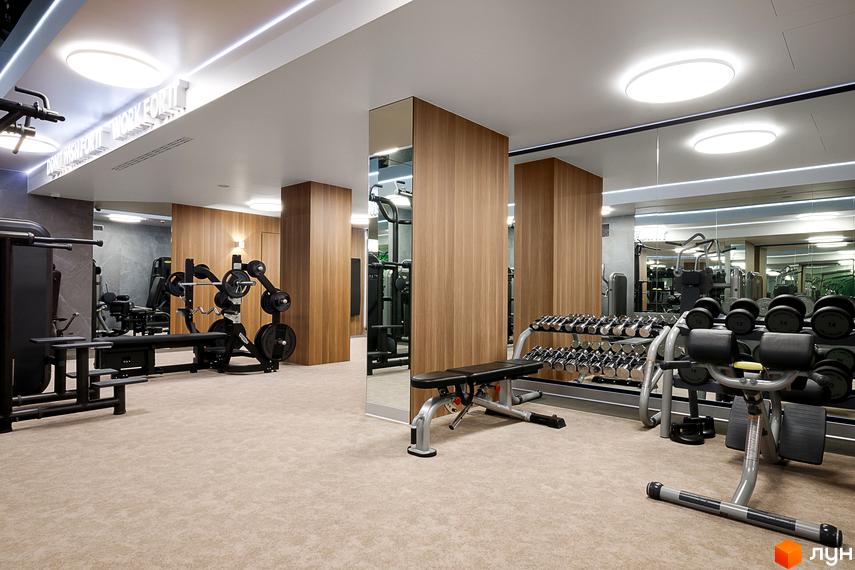 Тренажерний зал житлового комплексу Obolon Residences з гантелями, лавами для жиму та силовими тренажерами. Просторе приміщення з дзеркалами та світлим покриттям підлоги.