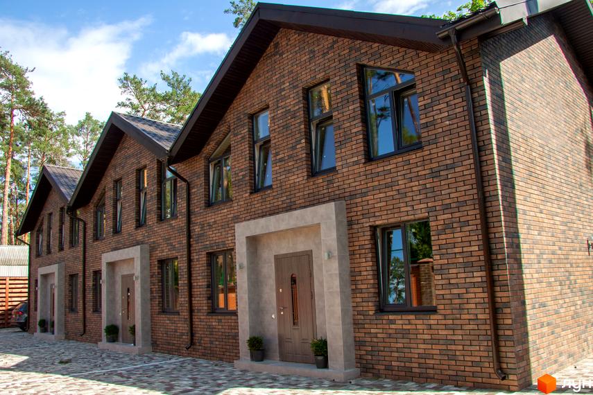 Таунхаус „На Кочубея“ – цегляні будинки з темними вікнами та дахами, розташовані на фоні дерев. Перед будинками облаштований двір з бруківкою та зеленими насадженнями.