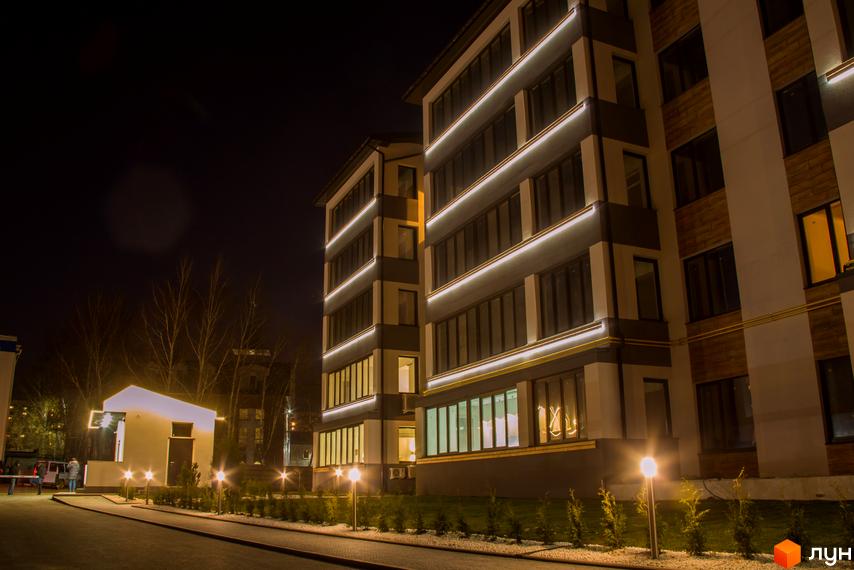 Фото фасаду ЖК Cофія вночі з підсвіткою. На передньому плані освітлена прибудинкова територія з ліхтарями та зеленими насадженнями.