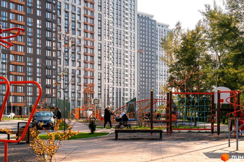 Житловий комплекс Seven: фасади будинків з панорамними вікнами та балконами. Поруч дитячий майданчик та зелена зона.