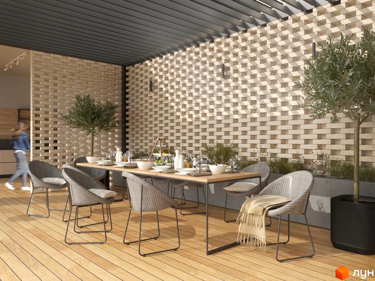 Клубний будинок Community: простора тераса з обіднім столом та плетеними кріслами під перголою з цегляною стіною. Зелені насадження та дерево додають затишку.