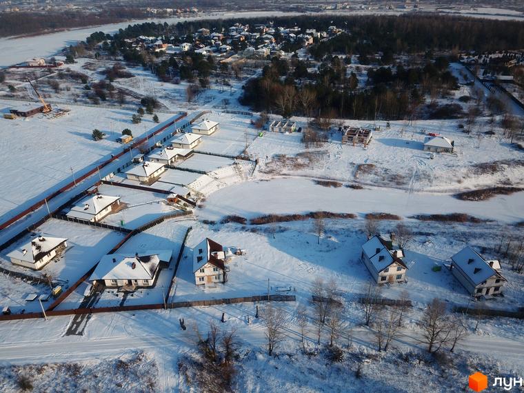 Котеджне містечко КМ Маєток у зимовому ландшафті. Засніжені будинки з черепичними дахами та огороджені ділянки.