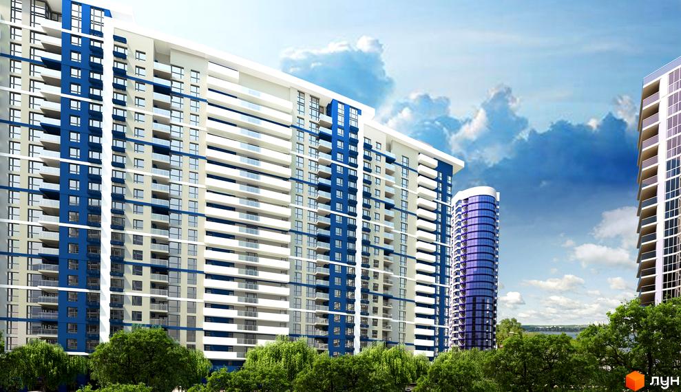 Житловий комплекс Зарічний - сучасна архітектура з синіми та бежевими фасадами, скляними балконами та зеленими деревами на фоні блакитного неба.