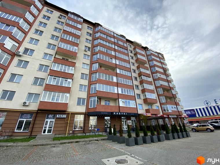 Зовнішній вигляд багатоповерхового будинку на вулиці Стуса / Миколайчука. Прибудинкова територія з тротуарною плиткою та декоративними рослинами.