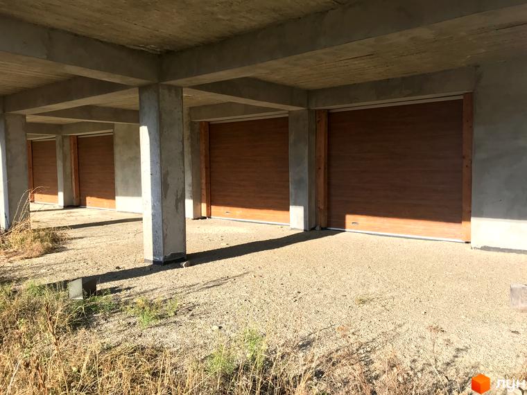 Котеджне містечко КМ Семидвір: фасади будинків з дерев'яними елементами та територія з гравійним покриттям.