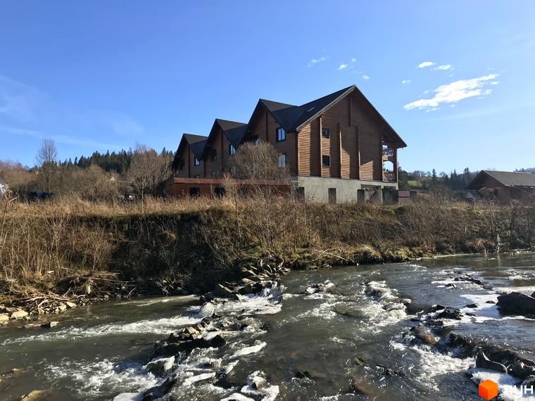 Котеджне містечко КМ Семидвір - дерев'яні будинки біля річки з гірським пейзажем. Навколо зелені насадження та чисте повітря.