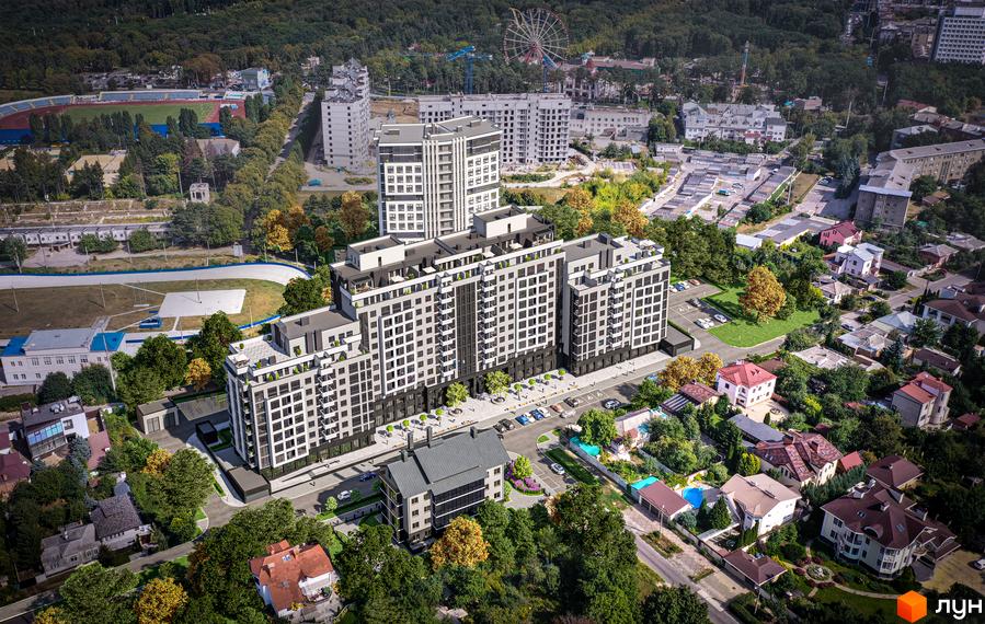 Новобудова ЖК Авіаційний з біло-сірими фасадами та великою кількістю вікон, розташована біля зеленої зони та спортивного стадіону.