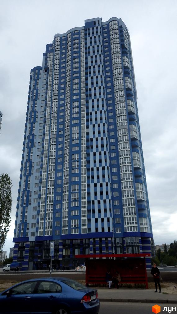 Житловий комплекс Київська Венеція з сучасним фасадом у блакитних тонах. Прибудинкова територія з зупинкою громадського транспорту.