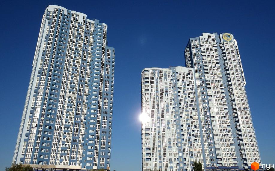 Житловий комплекс Київська Венеція - висотні будинки з блакитними та білими фасадами, багато вікон та балконів. Сонячний день, чисте блакитне небо.