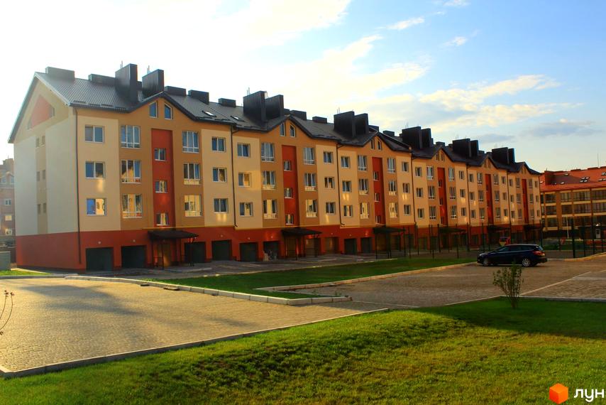 Зображення фасаду будинку на вулиці Проектована-Тролейбусна, 3. Вигляд на прибудинкову територію та парковку.