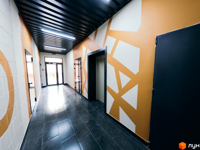 Сучасний коридор житлового комплексу на вулиці Транспортна, 10, з дверима та ліфтом. Дизайн стін з геометричними візерунками.