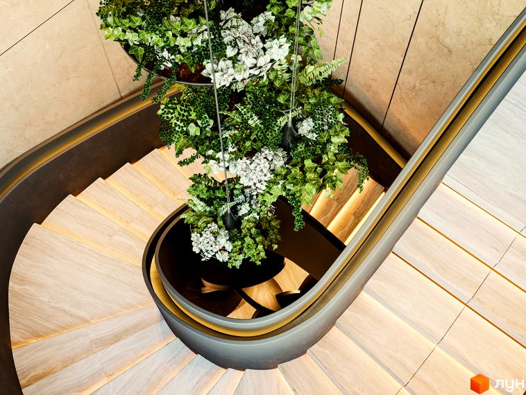 Сходи з підсвічуванням та натуральним каменем, доповнені зеленими рослинами, у холі Житлового комплексу Poetica. Перша колекція.