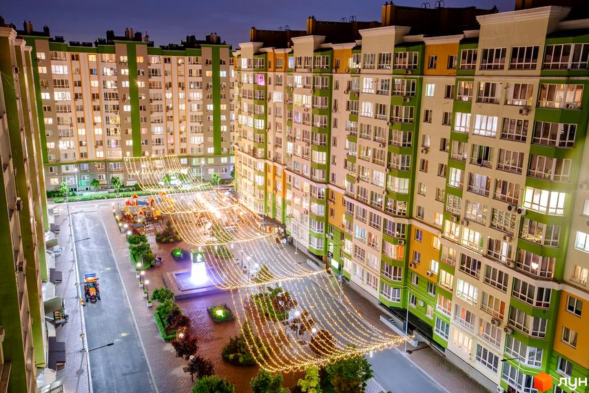 Житловий комплекс Евромісто з яскравою фасадною обробкою та святковою ілюмінацією. На прибудинковій території розташований дитячий майданчик та фонтан.
