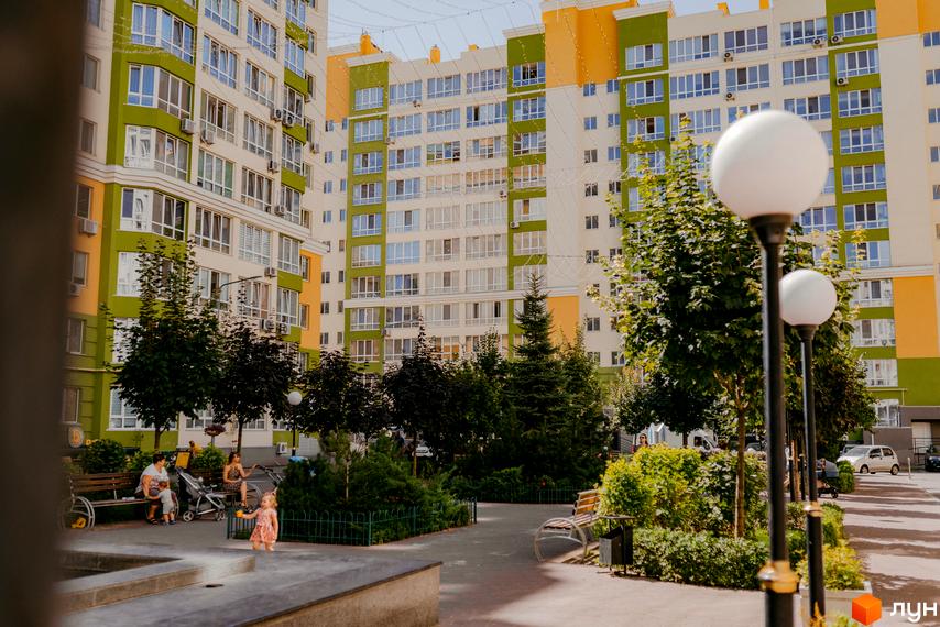Житловий комплекс Євромісто: багатоповерхові будинки з яскравими фасадами, зелені зони відпочинку та дитячий майданчик. Фото з прибудинкової території.