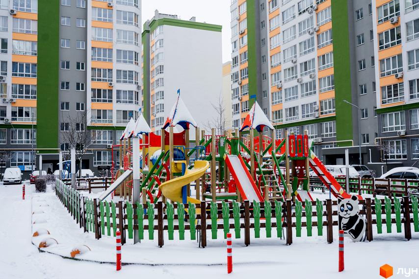 Житловий комплекс Евромісто: багатоповерхові будинки з яскравими фасадами та дитячий майданчик взимку. Новобудова з закритою територією та ігровими зонами.