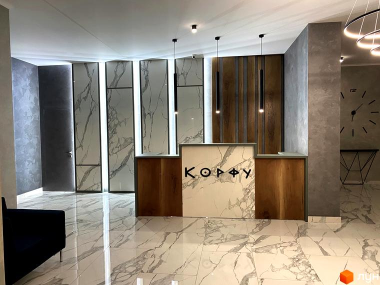 Рецепція Житлового комплексу Корфу з мармуровим оздобленням. Інтер'єр з дерев'яними панелями та підвісними світильниками.